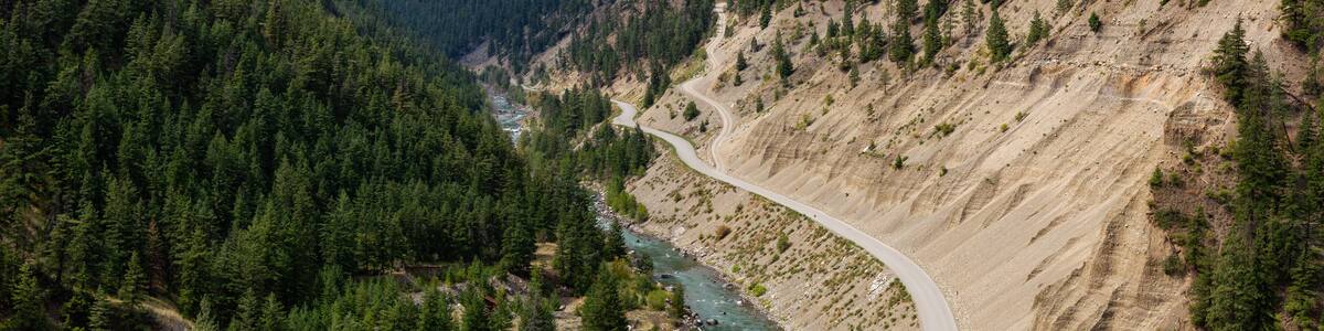 Aerial View of a Scenic Dirt Road towards Gold Bridge in the Valley surrounded by Canadian Mountain Landscape. Taken near Lillooet, British Columbia, Canada.