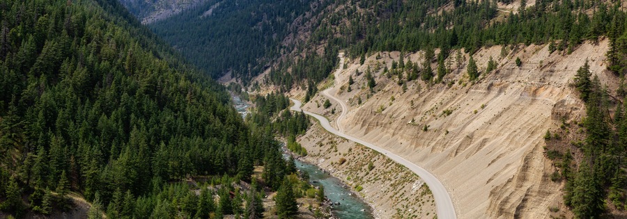 Aerial View of a Scenic Dirt Road towards Gold Bridge in the Valley surrounded by Canadian Mountain Landscape. Taken near Lillooet, British Columbia, Canada.