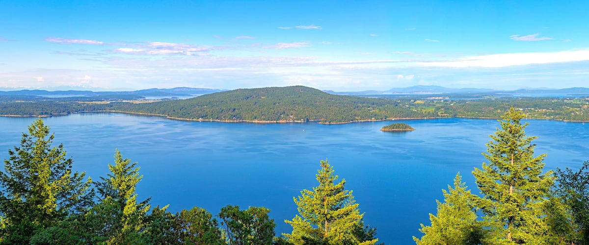 A large body of water surrounded by forested hills and mountains.