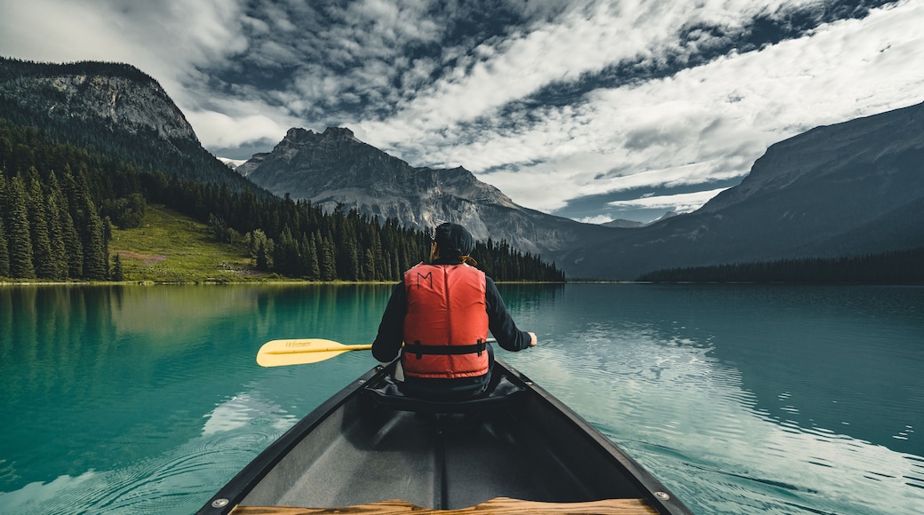 Young Man Canoeing on Emerald Lake in the rocky mountains canada with canoe and life vest with mountains in the background blue water.