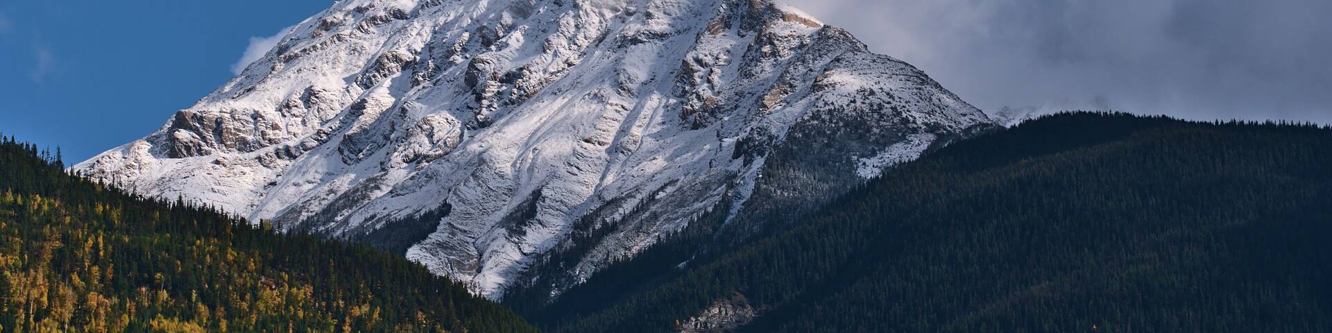 Beautiful view of rugged snow-capped mountain viewed from Robson Valley near McBride, British Columbia, Canada in autumn season with colorful forest.