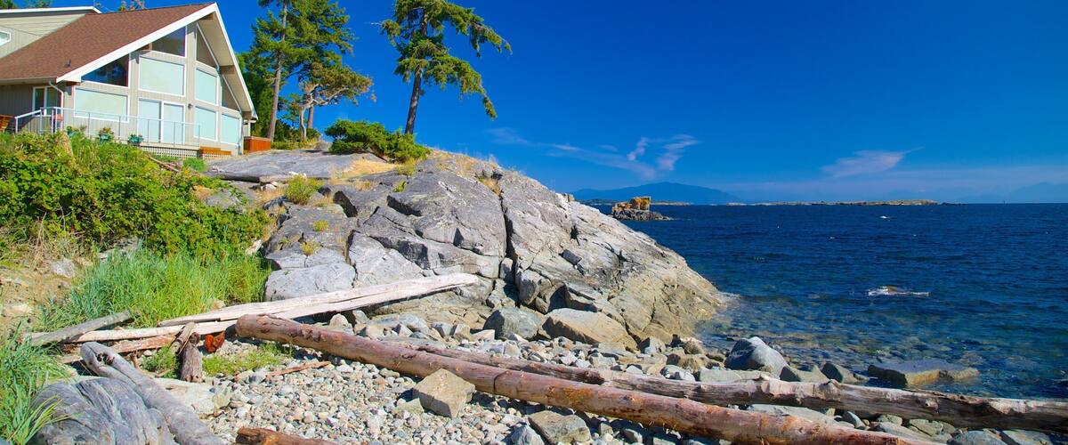 A coastal house with a rocky shoreline, clear blue sky, and calm sea.