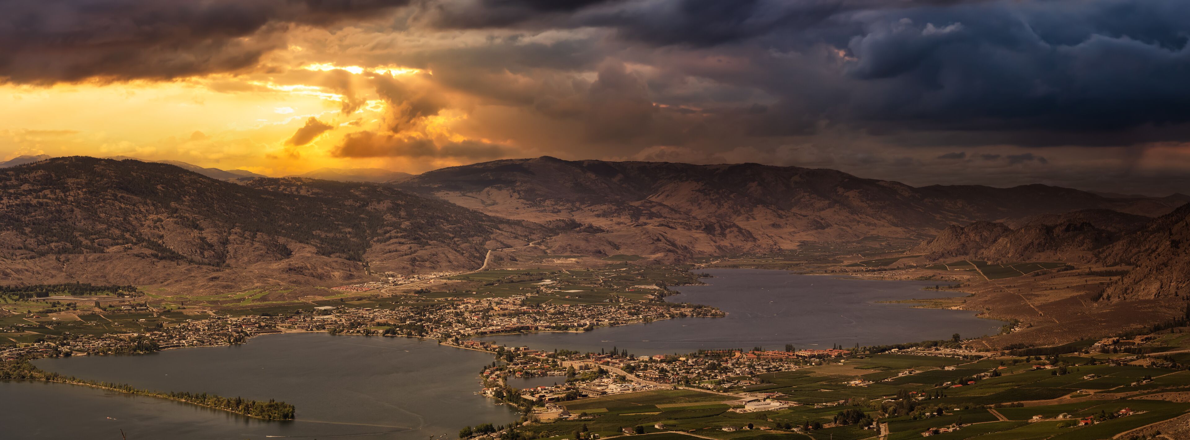 A mountainous landscape with a town and two lakes.
