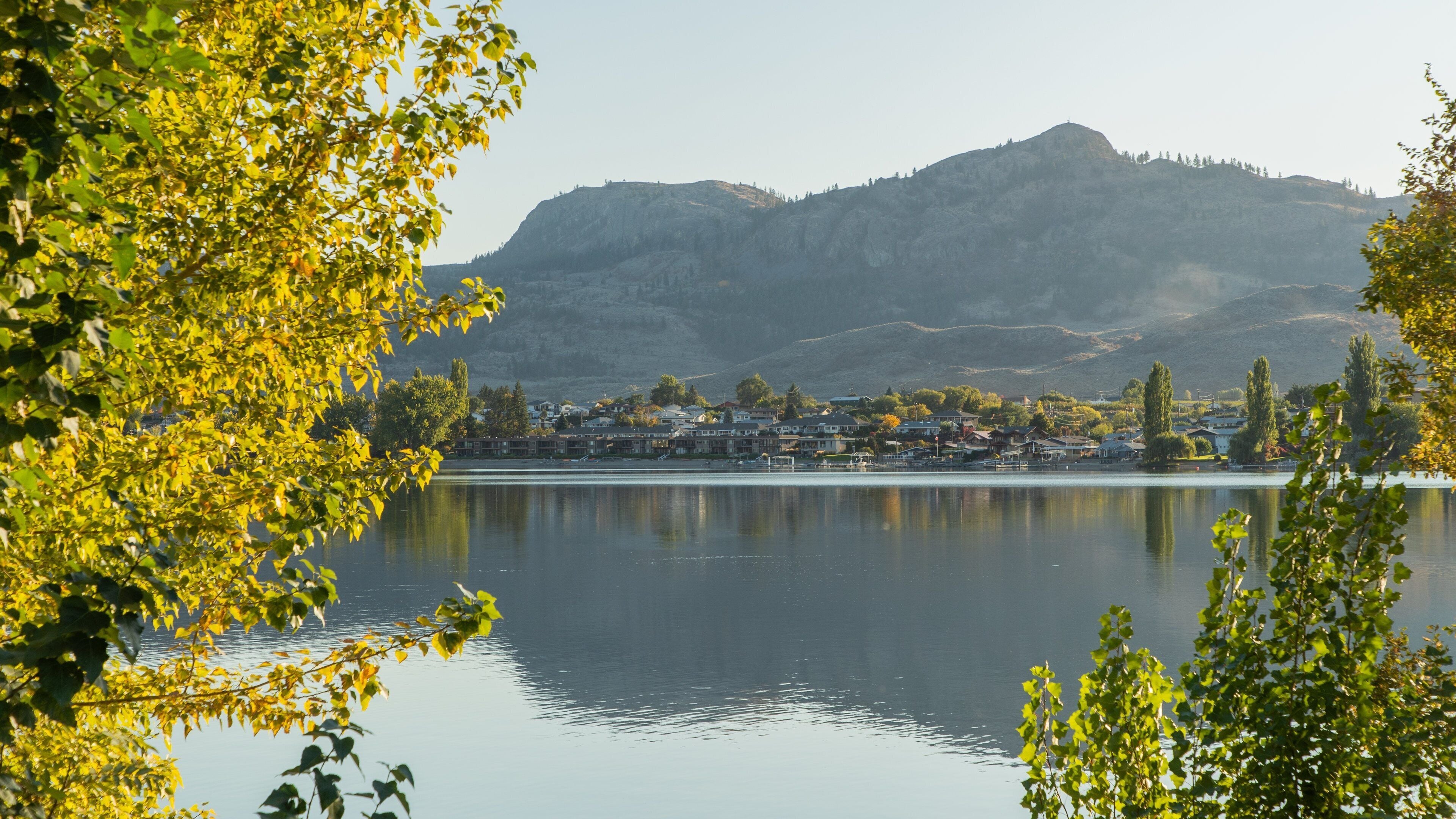 A calm lake with a town in the background and mountains.