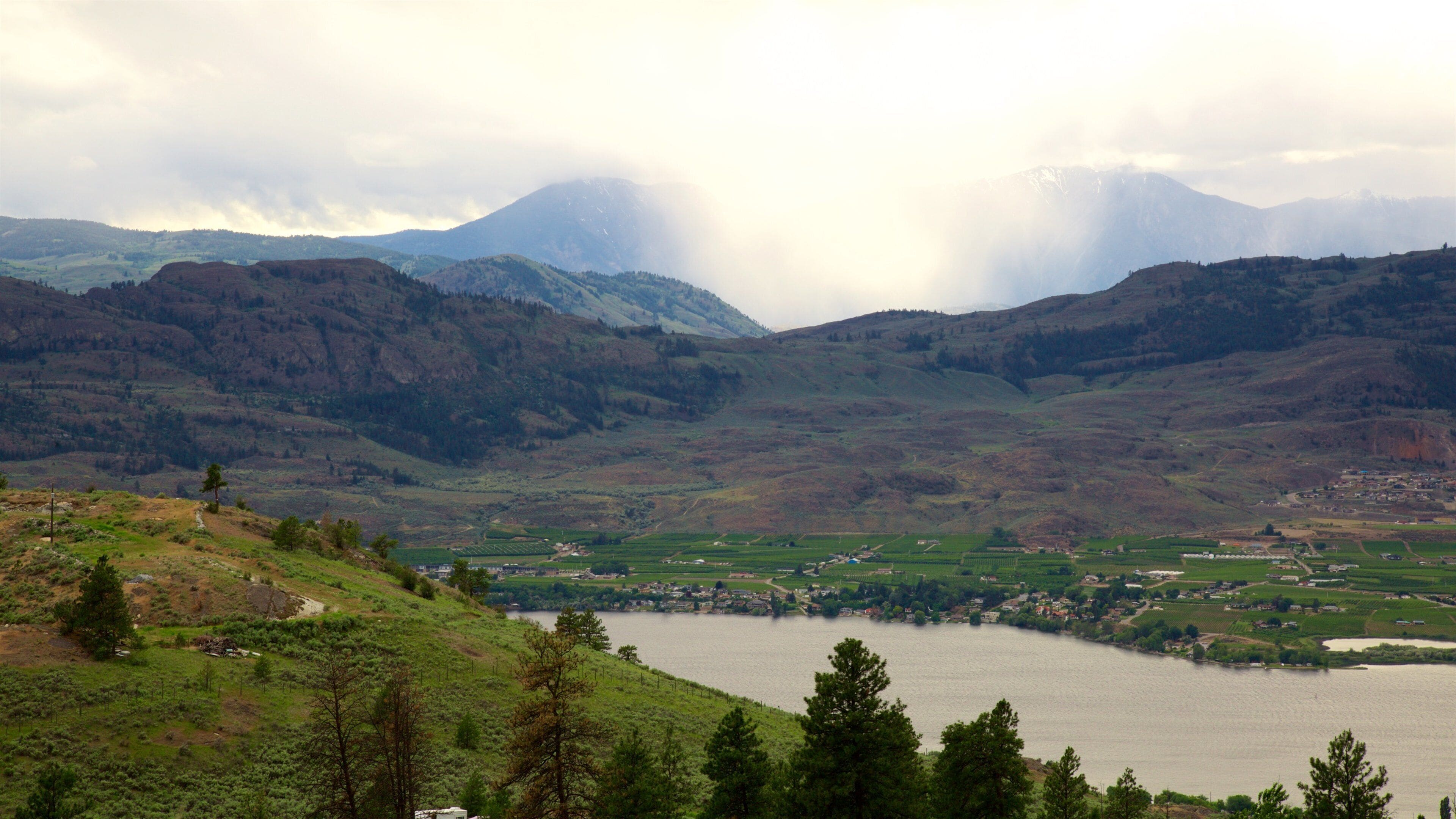 A valley with a lake surrounded by hills and mountains.