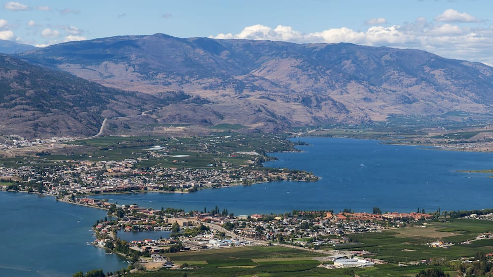 A town by a large lake surrounded by mountains.