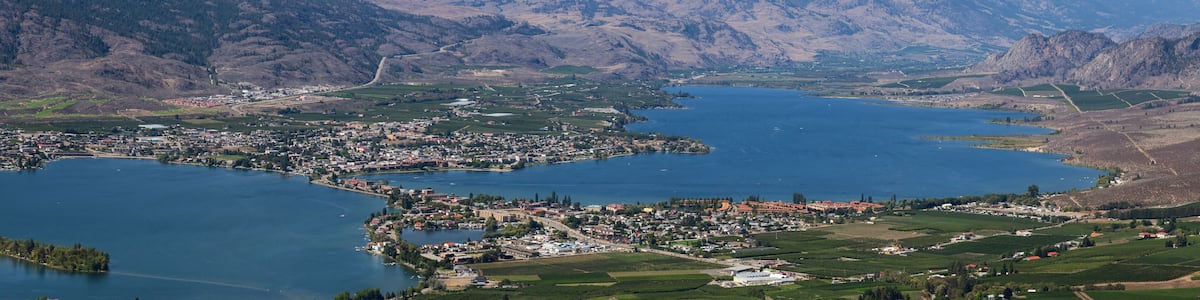 A town by a large lake surrounded by mountains.