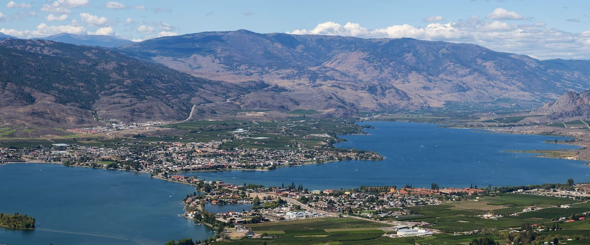 A town by a large lake surrounded by mountains.