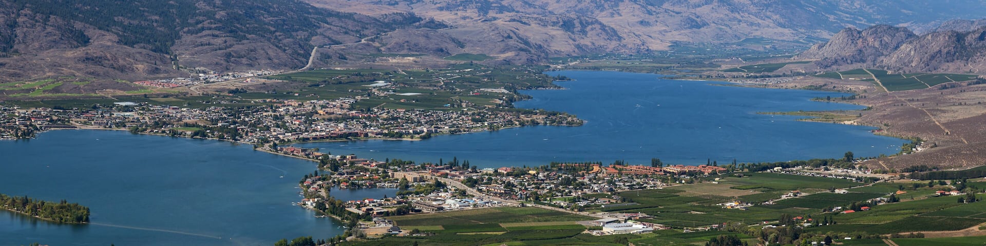 A town by a large lake surrounded by mountains.