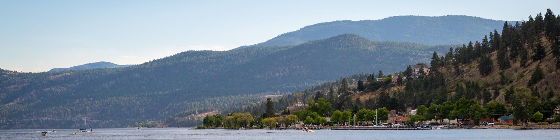 A kayaker on a calm lake with mountains in the background.
