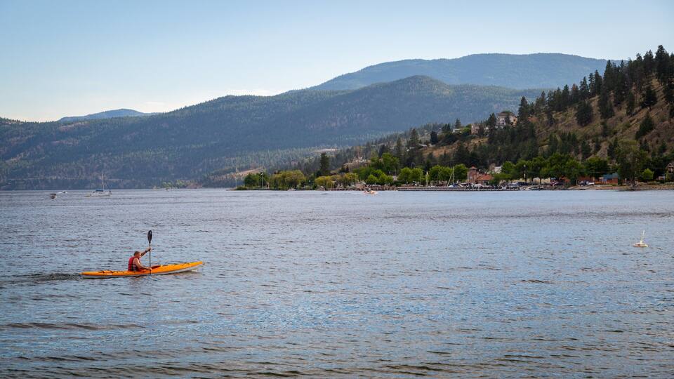 A kayaker on a calm lake with mountains in the background.
