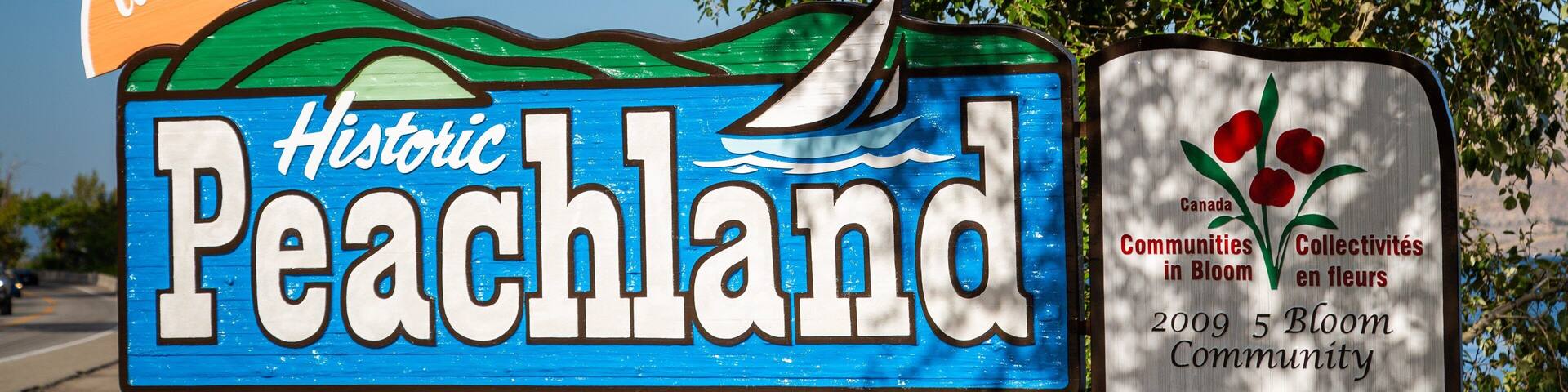 A sign for Historic Peachland with a sailboat and a welcome sign.