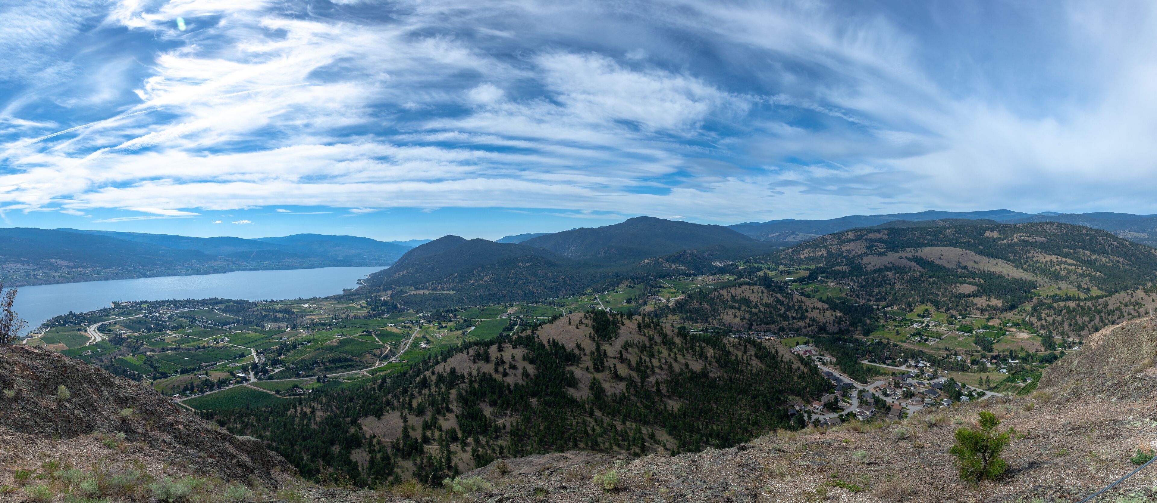 A mountainous landscape with a lake, green fields, and scattered houses.