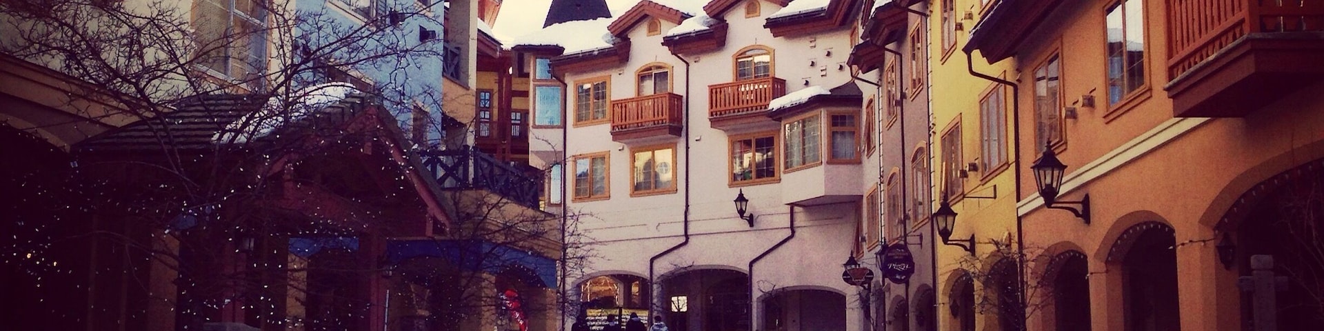 Eine verschneite Straße mit Gebäuden an beiden Seiten und einem Banner für Sun Peaks Resort.