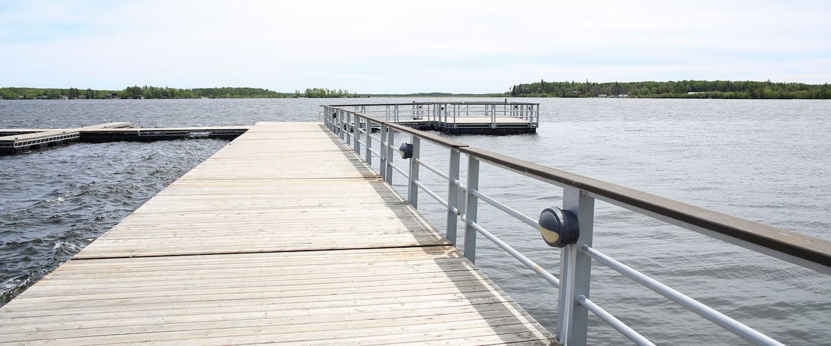 A wooden pier extending into calm water with a metal railing.