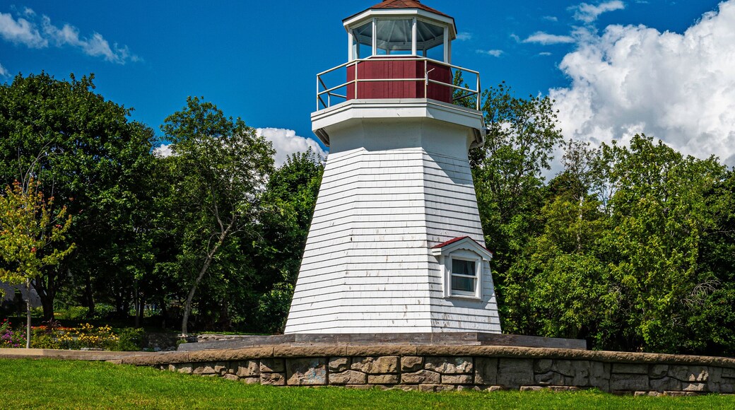 Renforth Lighthouse on the riverbank of Kennebecasis River in Rothesay, New Brunswick, Canada. Empty resting bench and tranquil cloudscape over summer green forest and hilly community park.