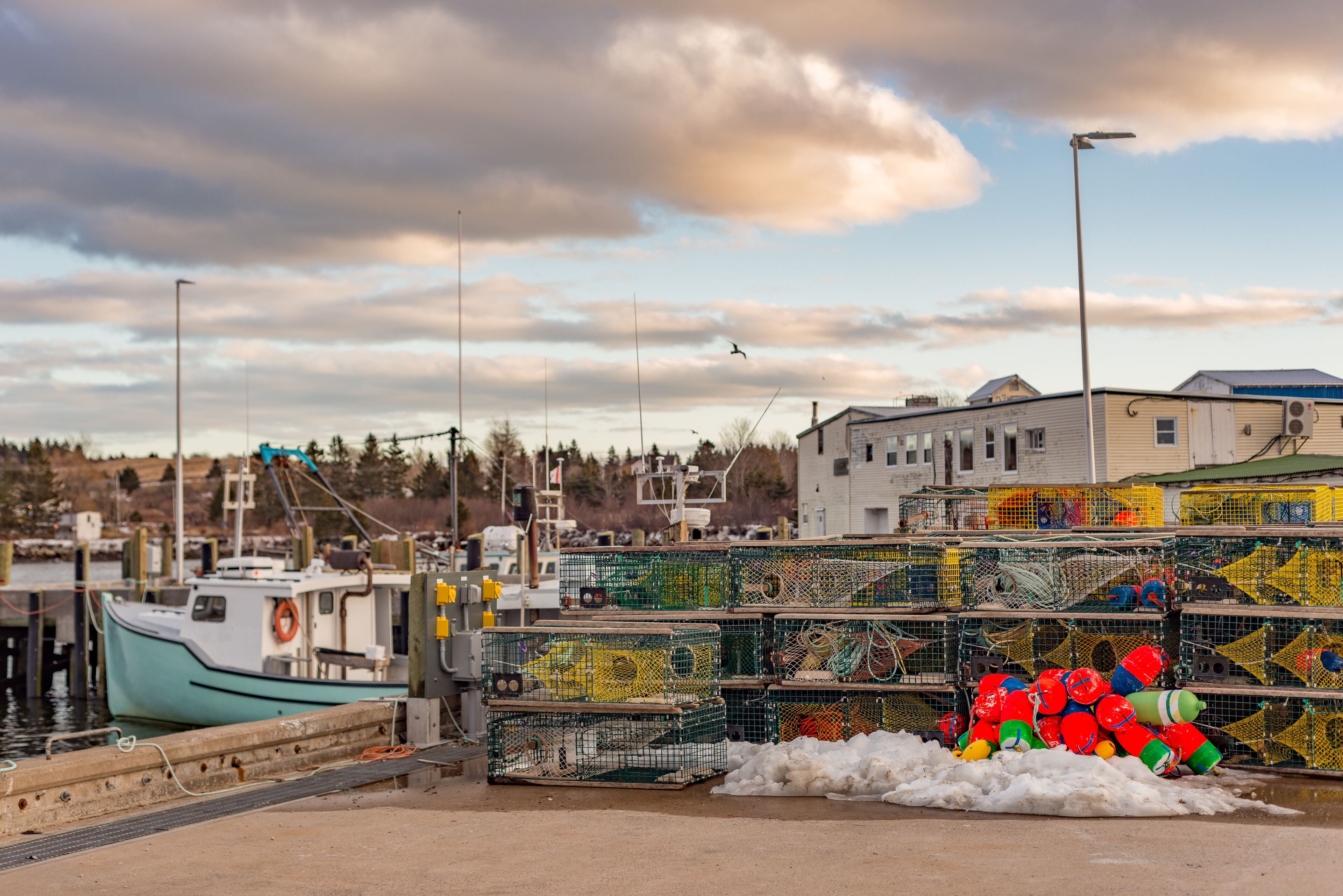 A harbor with a boat docked, fishing cages, and a building in the background.