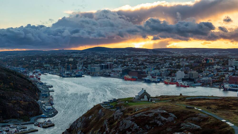 Un paysage urbain côtier avec une rivière, un port et des collines environnantes.