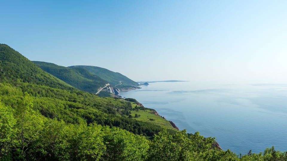 A coastal landscape with lush green hills and a clear view of the ocean.