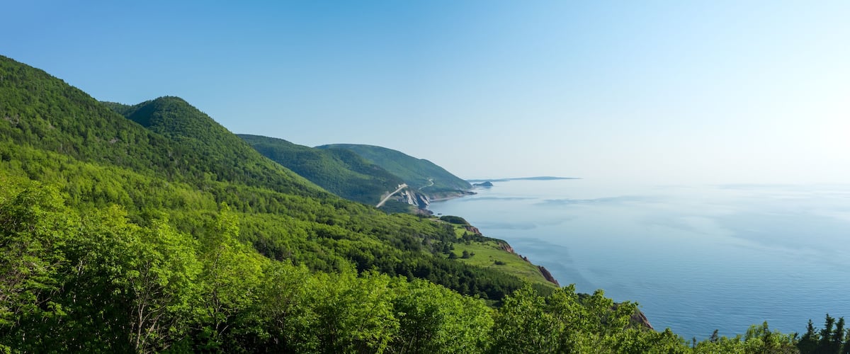 A coastal landscape with lush green hills and a clear view of the ocean.
