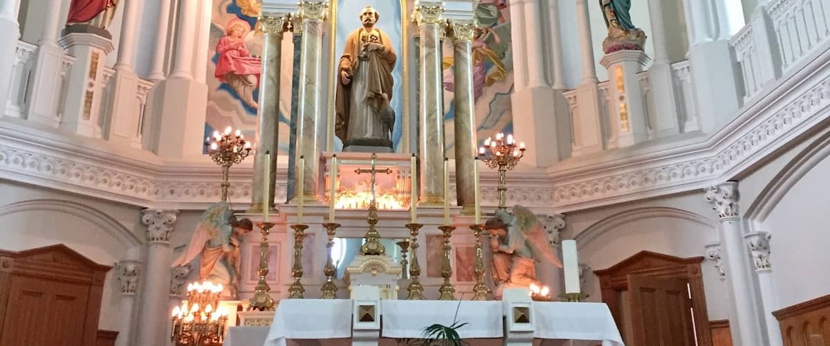 An ornate church interior with a central altar, religious statues, and detailed frescoes on the ceiling.