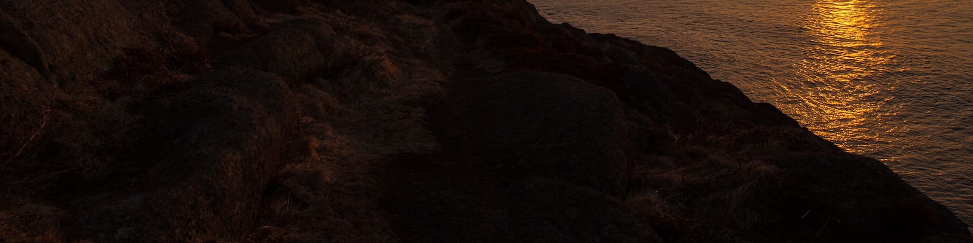 Photographer at Lighthouse at Ocean Sunrise Orange Horizon Blue Skies