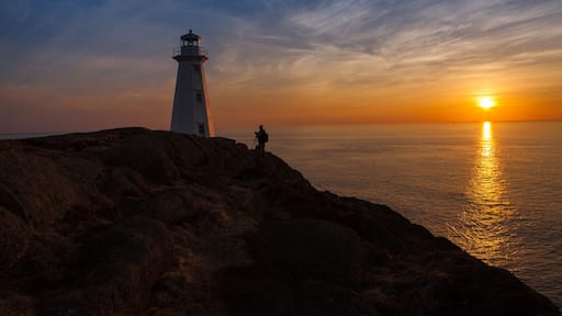 Photographer at Lighthouse at Ocean Sunrise Orange Horizon Blue Skies