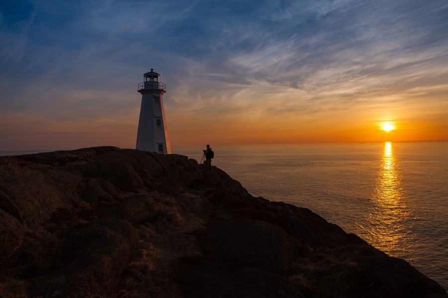 Photographer at Lighthouse at Ocean Sunrise Orange Horizon Blue Skies