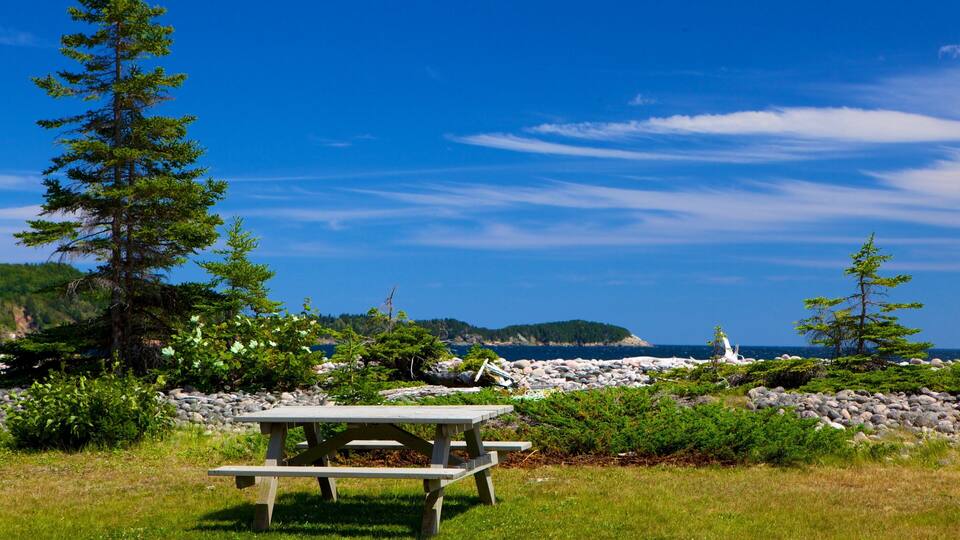 A picnic table by a rocky shoreline with a clear blue sky and distant mountains.