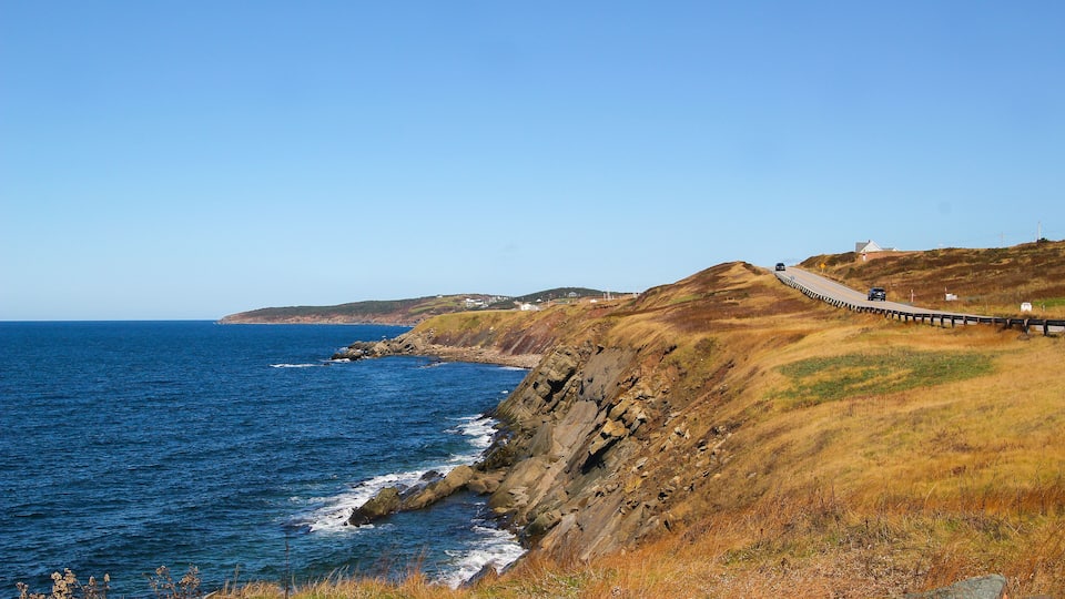 A coastal road with a wooden walkway along a cliffside.