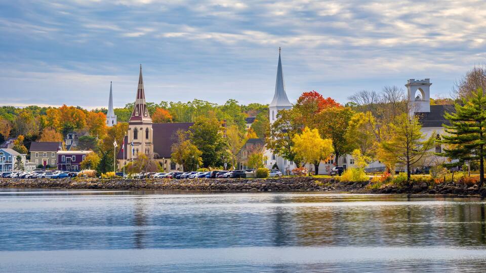 A lake with a church and a steeple in the background.