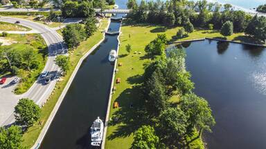 A river with a boat, a bridge, and a park with trees and grass.