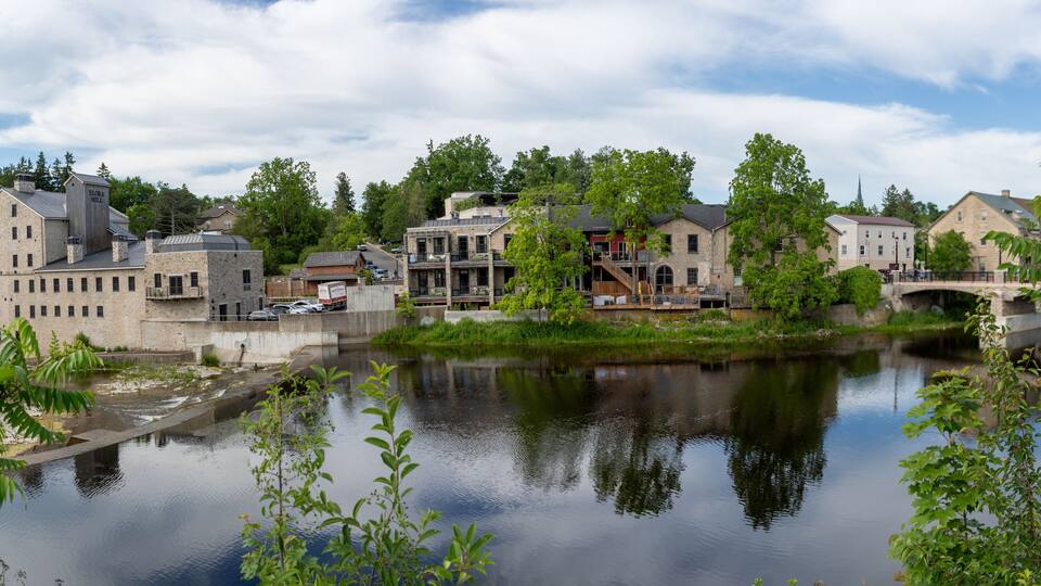 A riverside town with historic buildings, a bridge, and lush greenery.