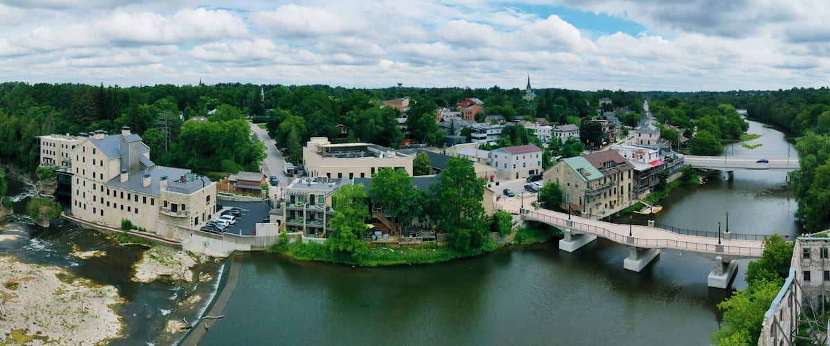 A riverside town with a bridge, buildings, and a church steeple.