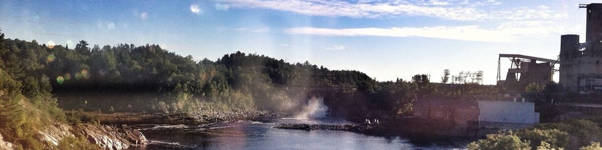 Hard to see in the distance but there's a cool dam way back.
I tried to get a shot of the massive factory beside it - but was blurry through the window.
So far I've counted 4 waterfalls and several dams along the Trans-Canada Hwy. also seen a beautiful hawk sitting atop a hay pile (would have made a great photo, and a few Hurons.
Anyone taking this trip with Greyhound Busses, a word of caution - Sudbury station is very sketchy, no coffee, dirty washrooms, vending machines only, and your in the middle of no where with homeless walking around. Keep an eye in your belongings at all times.
Almost approaching Sault Ste Marie Ontario (where I was born). Ironic enough I haven't lived here since I was a toddler and now I'm back on my birthday. Kinda cool I think.