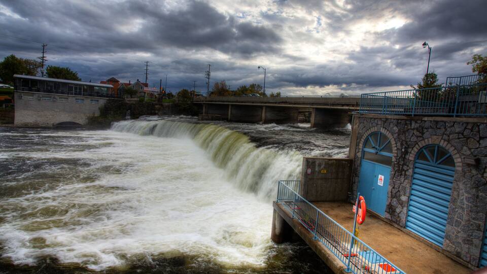 A waterfall, a bridge, and a stone building with blue doors.