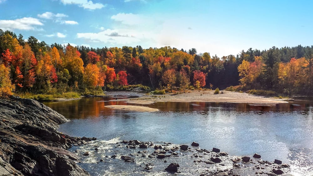 A river surrounded by autumn-colored trees and rocky terrain.
