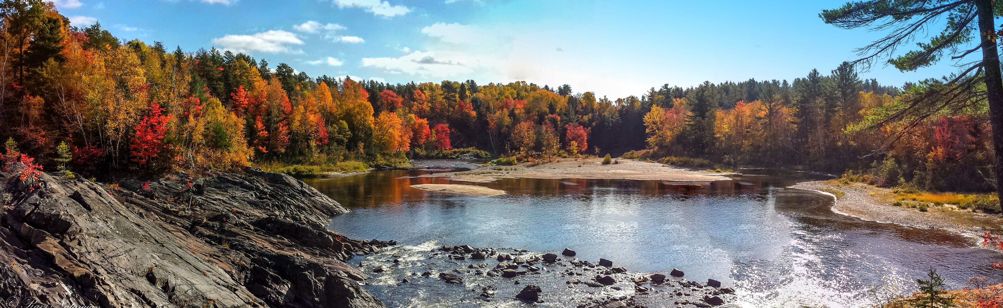 A river surrounded by autumn-colored trees and rocky terrain.