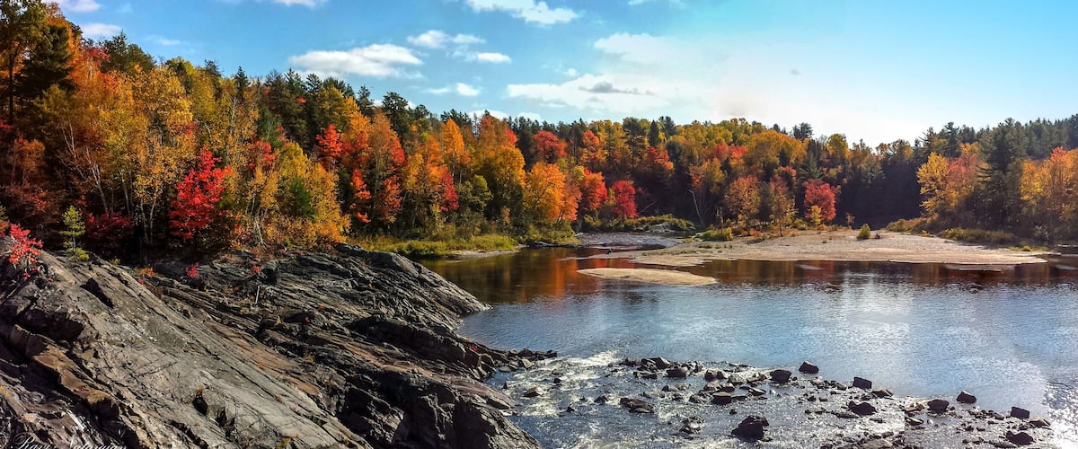 A river surrounded by autumn-colored trees and rocky terrain.