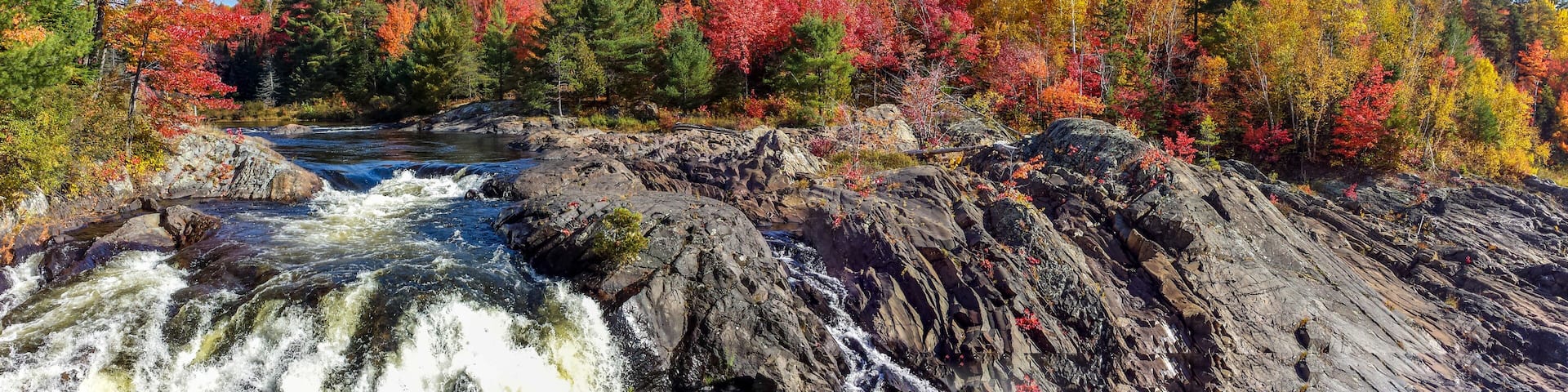 Panoramic view of the wild river flowing amidst rugged rocks and beautiful fall leaves, Massey, ON, Canada