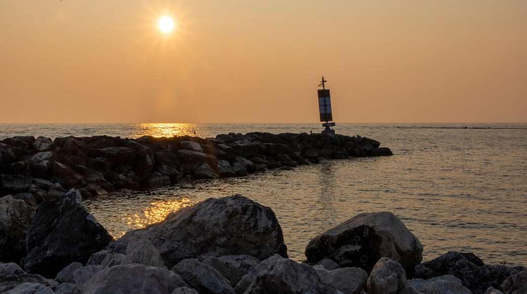 The sun sets over Lake Huron in Port Elgin, Ontario with one of the beach's breakwaters in the foreground.