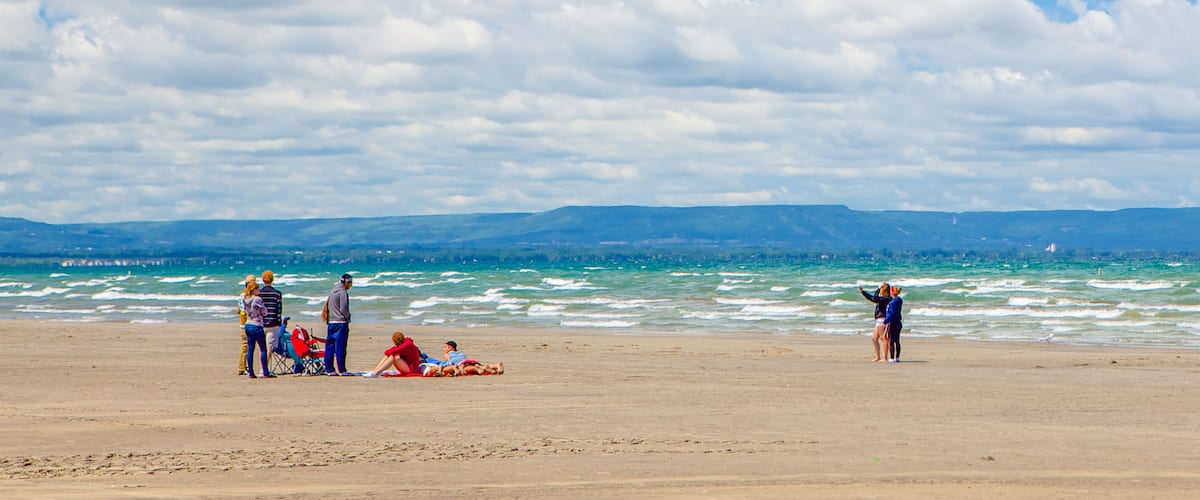 Una playa con gente relajándose y caminando junto al agua.