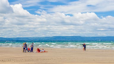 A beach with people relaxing and standing by the water.