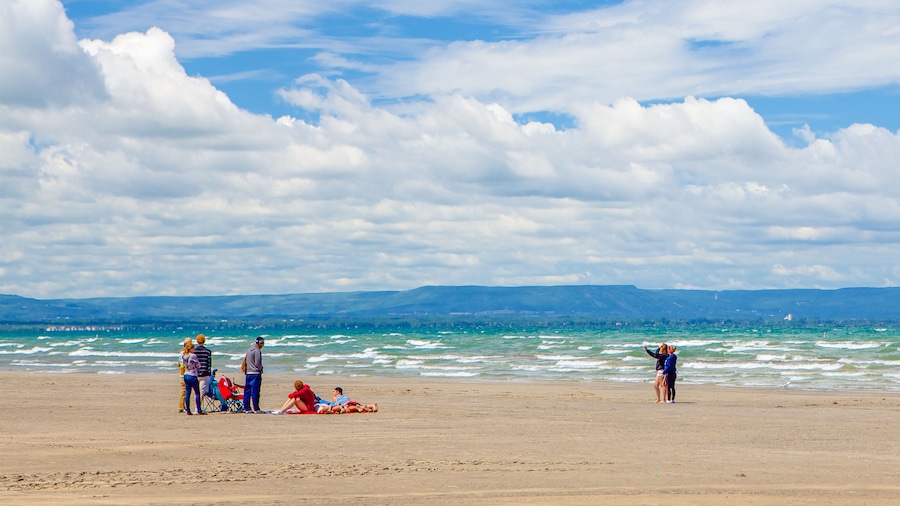 A beach with people relaxing and standing by the water.