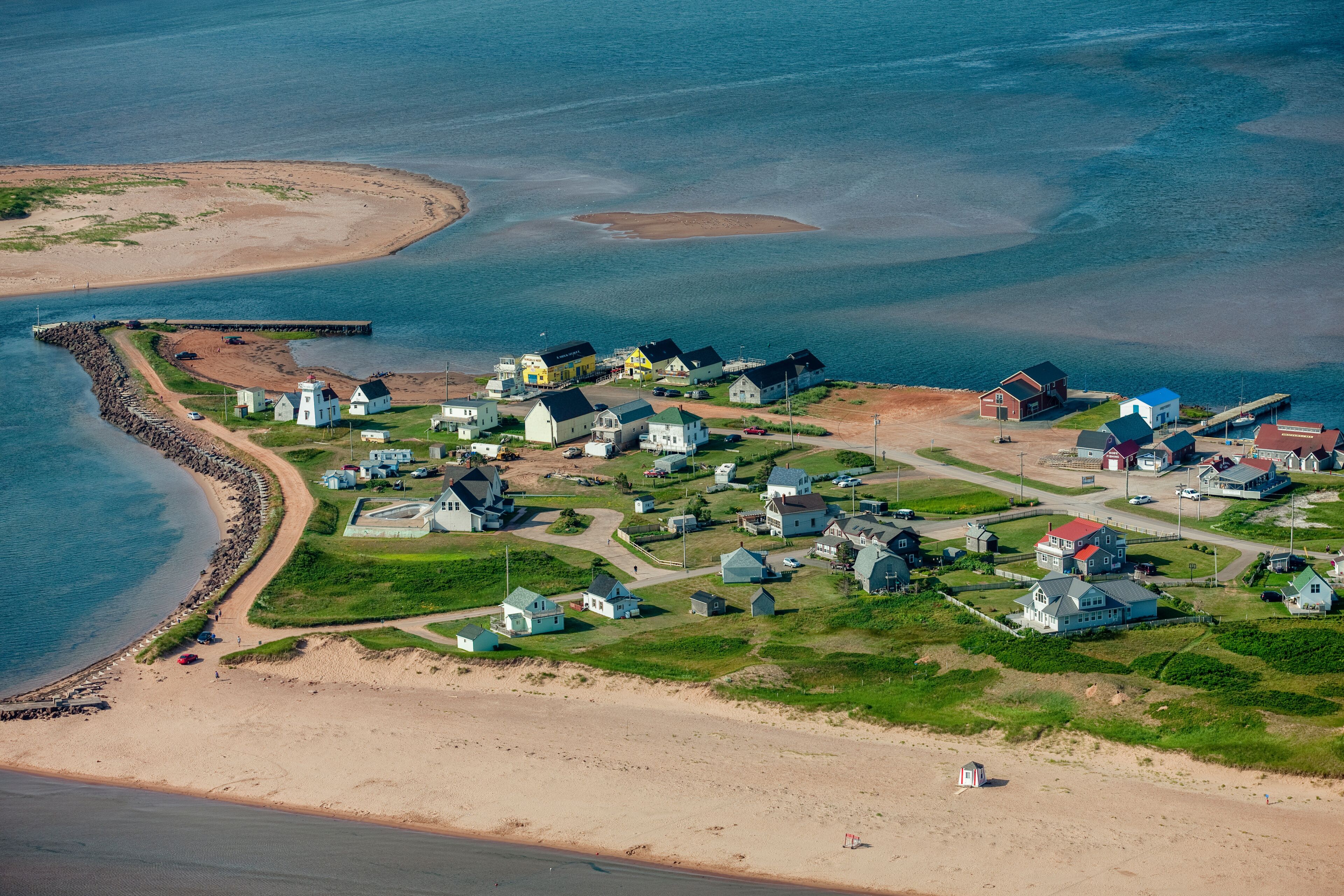 A coastal village with houses, a lighthouse, and a beach.