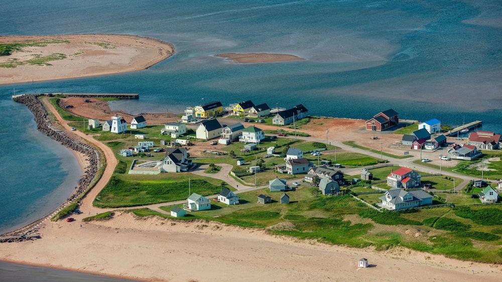 A coastal village with houses, a lighthouse, and a beach.