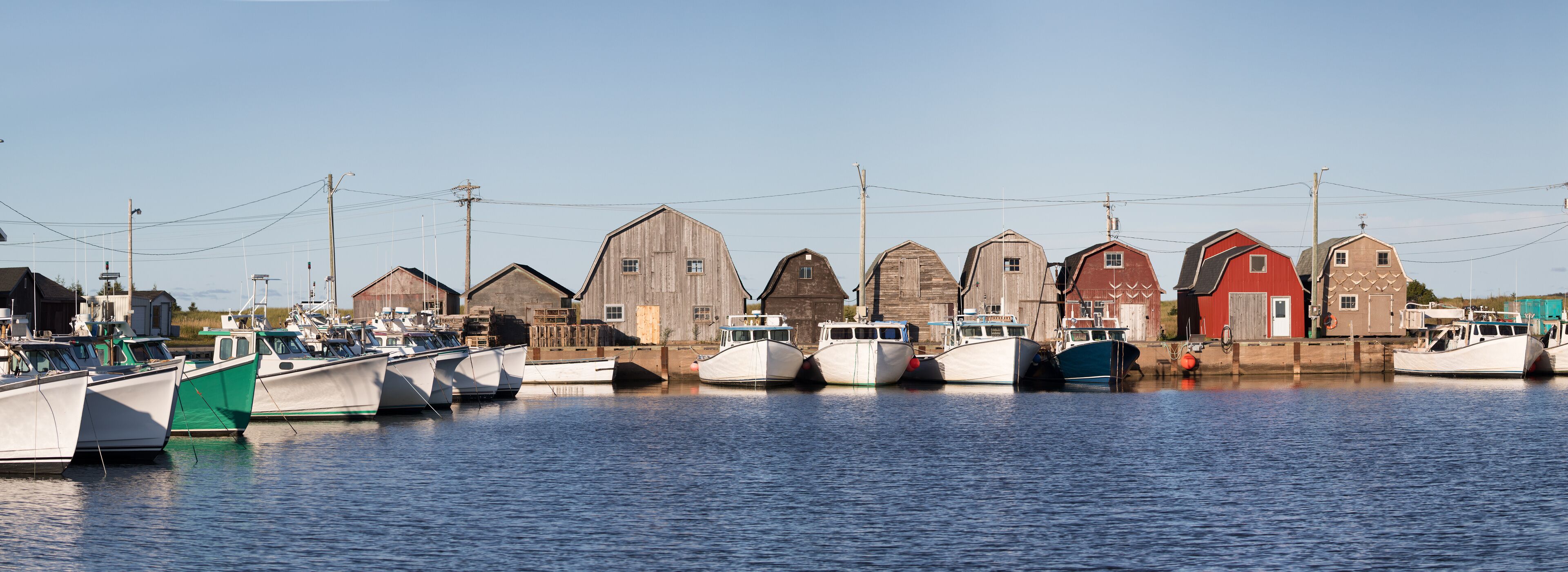 A harbor with several wooden boats docked and a row of old wooden buildings.