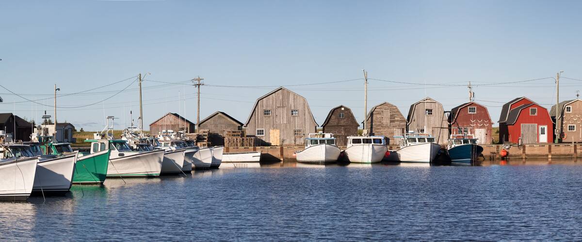 A harbor with several wooden boats docked and a row of old wooden buildings.