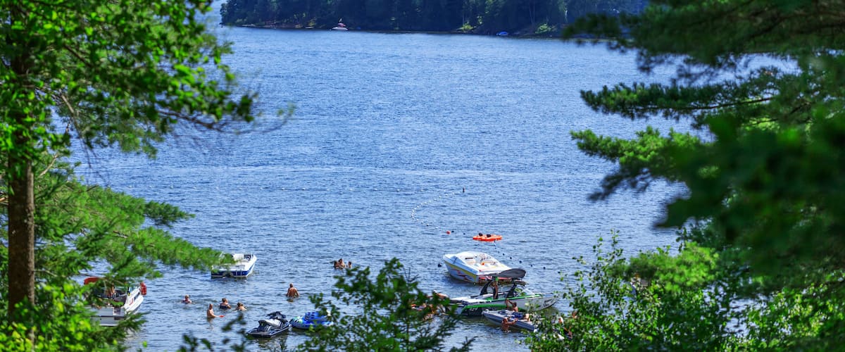A lake surrounded by dense forest with several boats and people on the water.