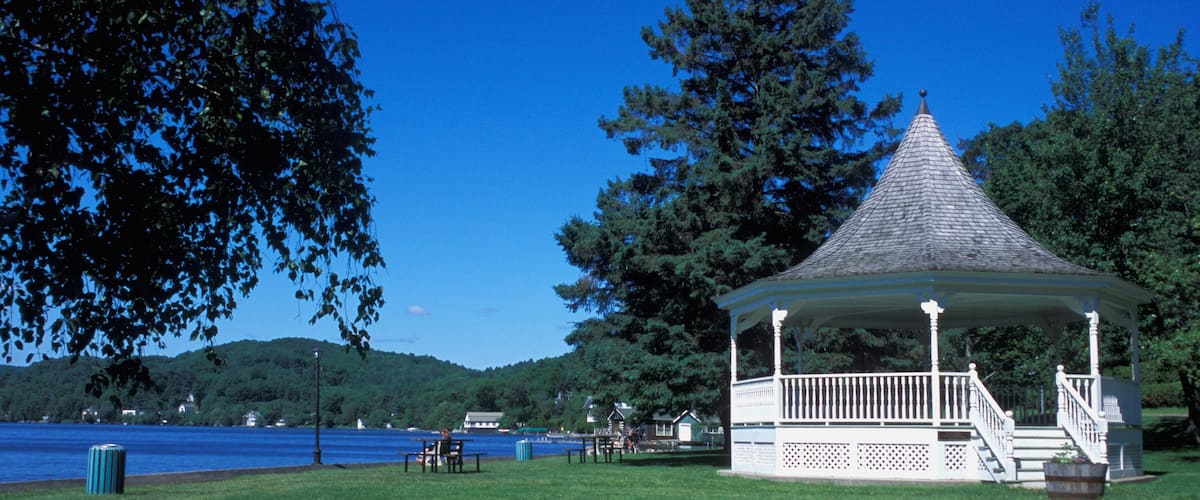 A gazebo by a lake with a clear blue sky.